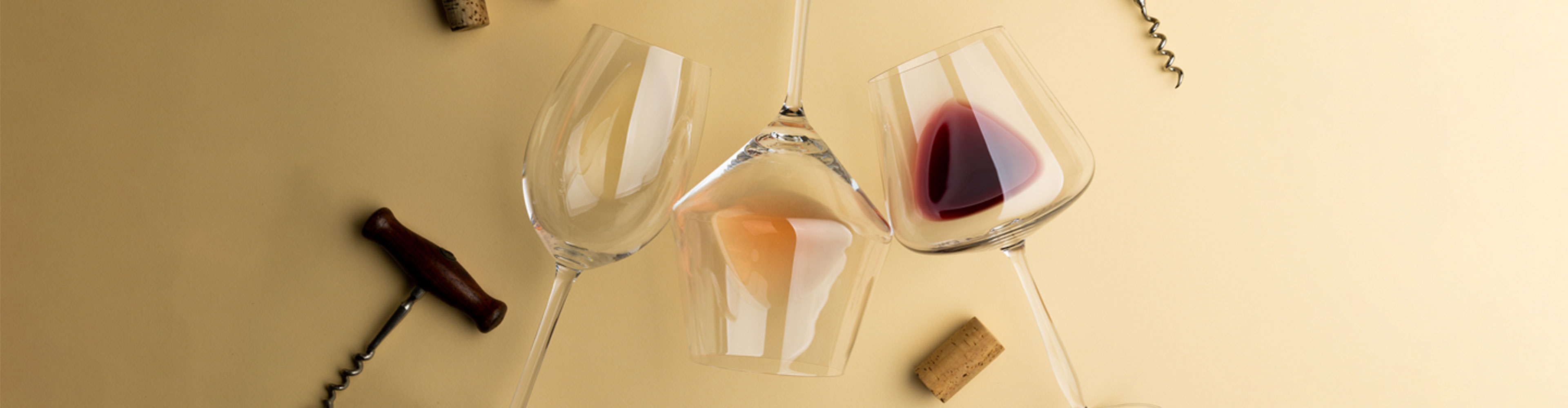 Rotwein- und Weißweingläser mit Flaschenöffner auf einem beigen Hintergrund.